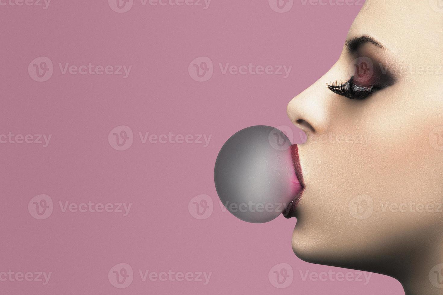 belle femme soufflant du chewing-gum rose. portrait en gros plan photo