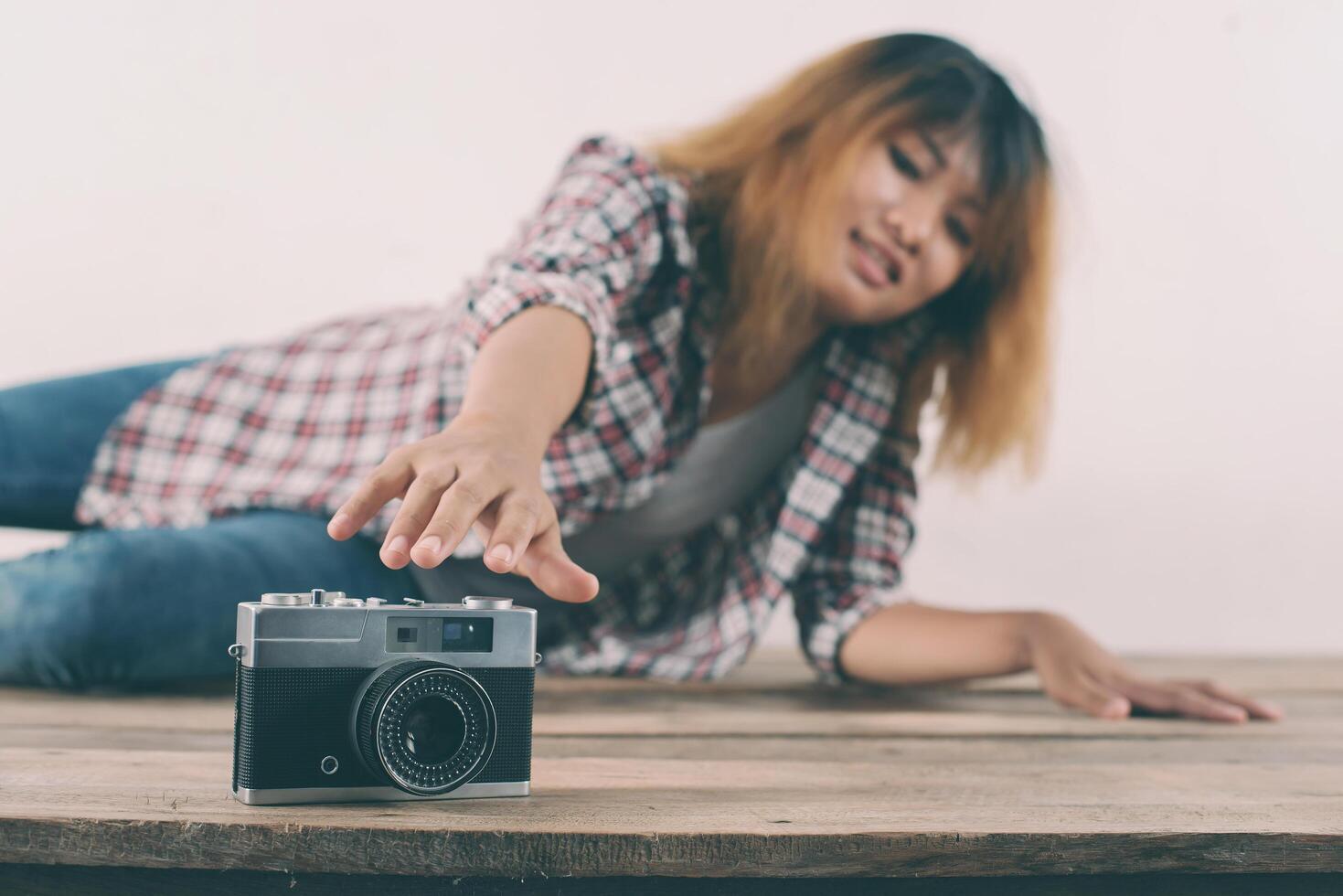 jeune femme hipster part tendre la main pour attraper un appareil photo rétro.