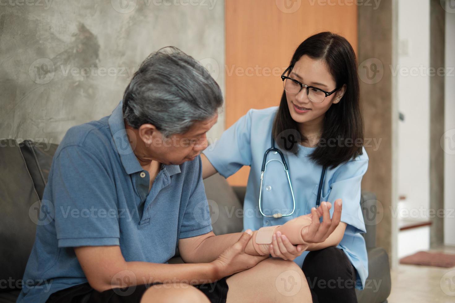 Un médecin thérapeute féminin examine un patient âgé à la maison. photo