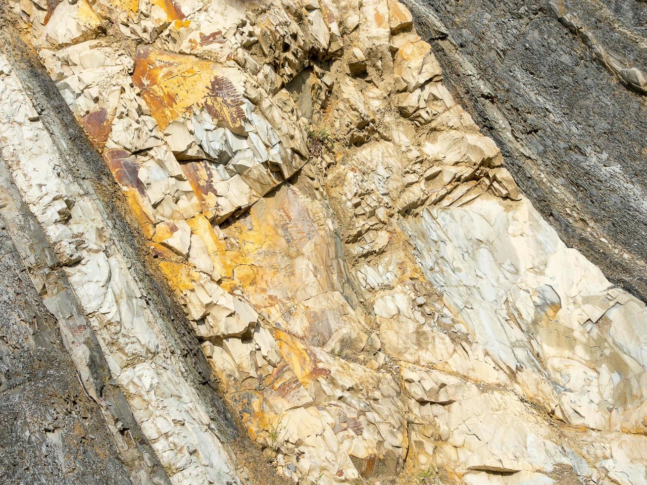 Roche de montagne de pierres de couleur grise, blanche et brune en couche en diagonale photo