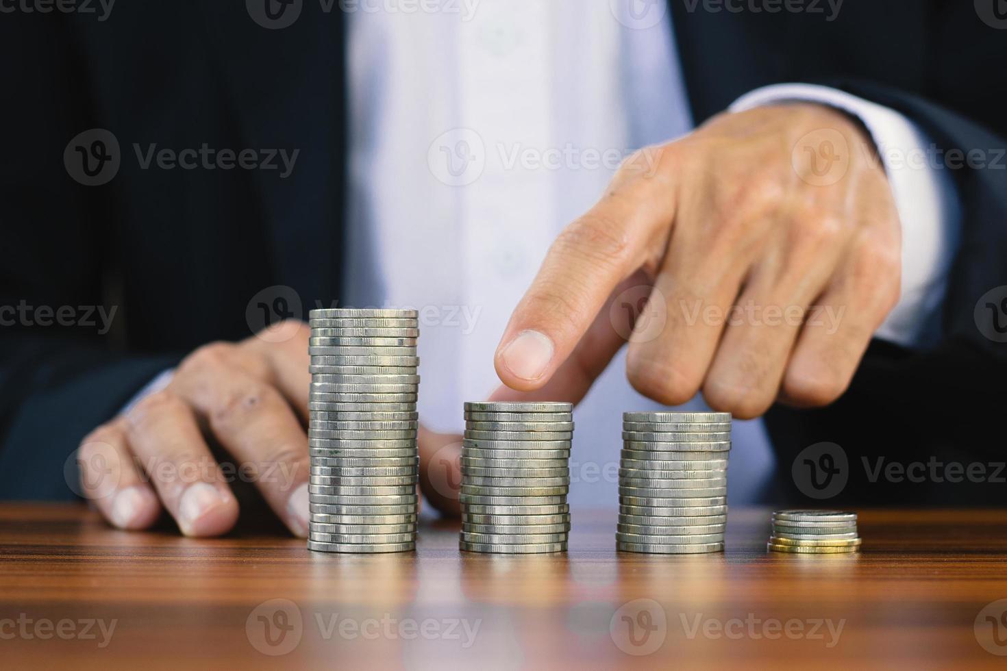 homme d'affaires touche sur la pile de pièces sur table en bois photo