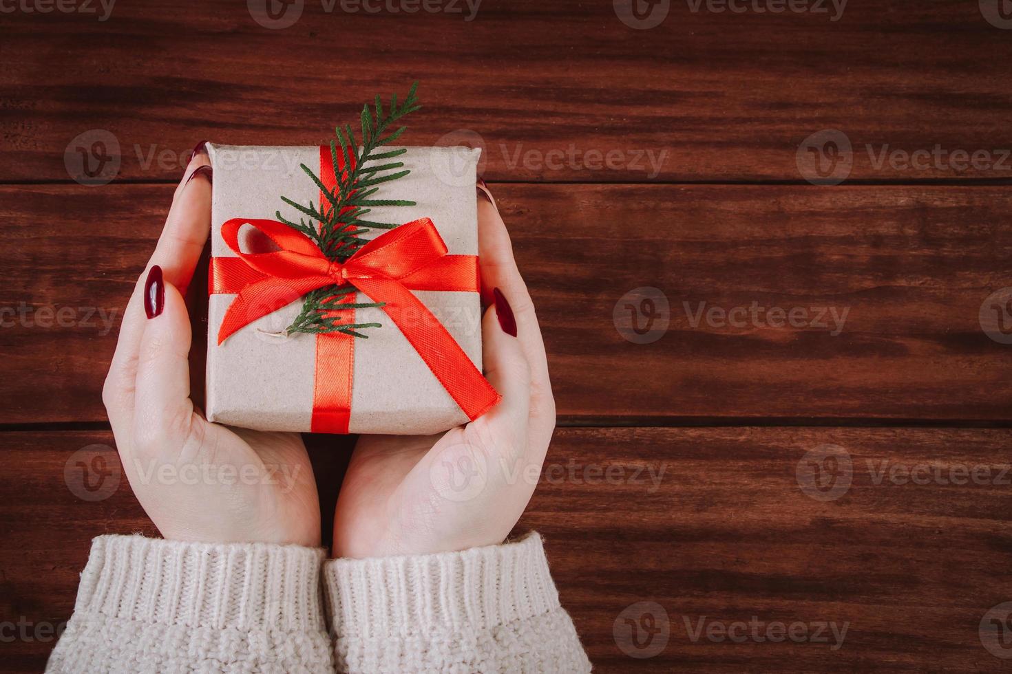 les mains tiennent une belle boîte-cadeau sur fond en bois. photo