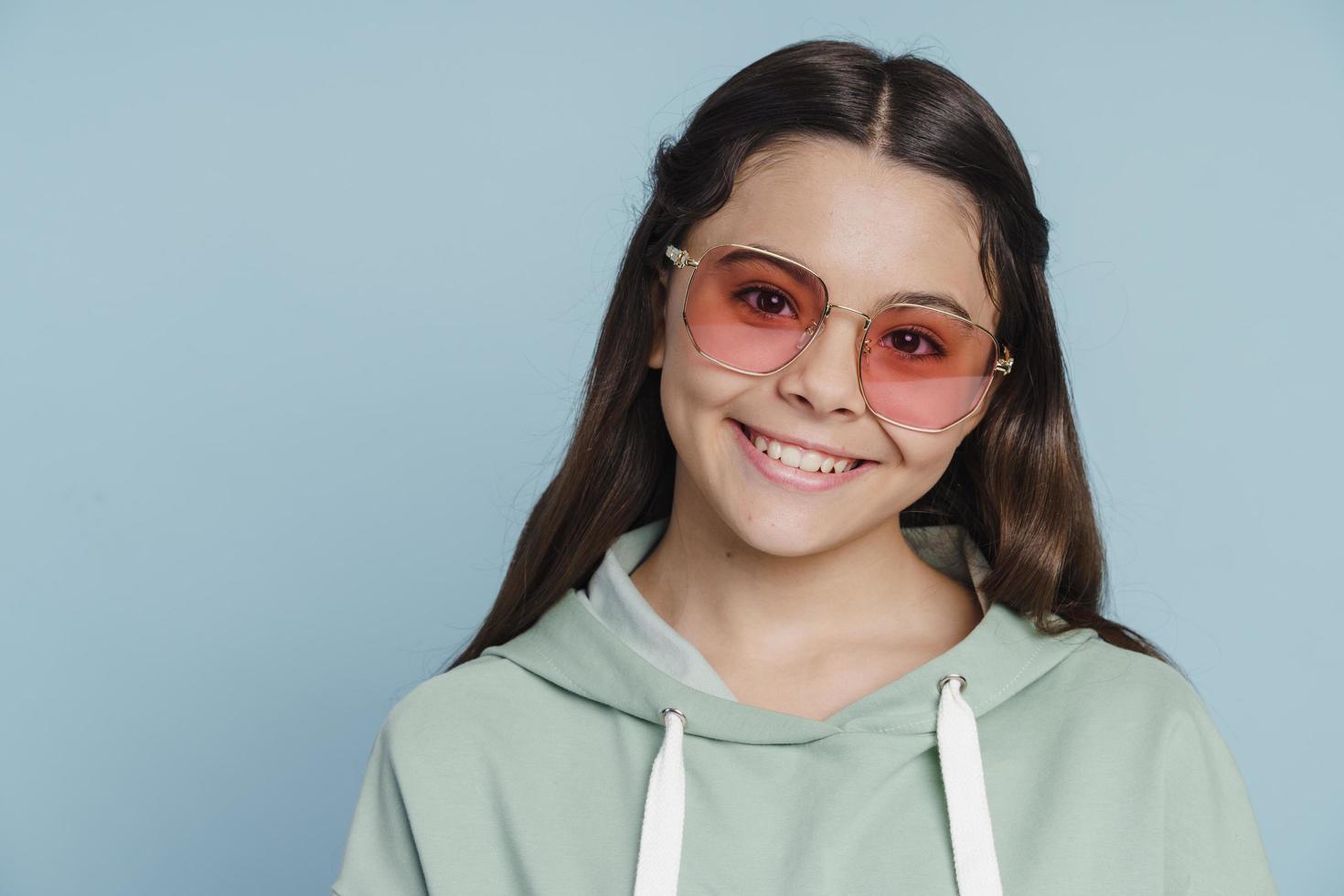 Une adolescente mignonne et attirante à lunettes de soleil regarde la caméra photo