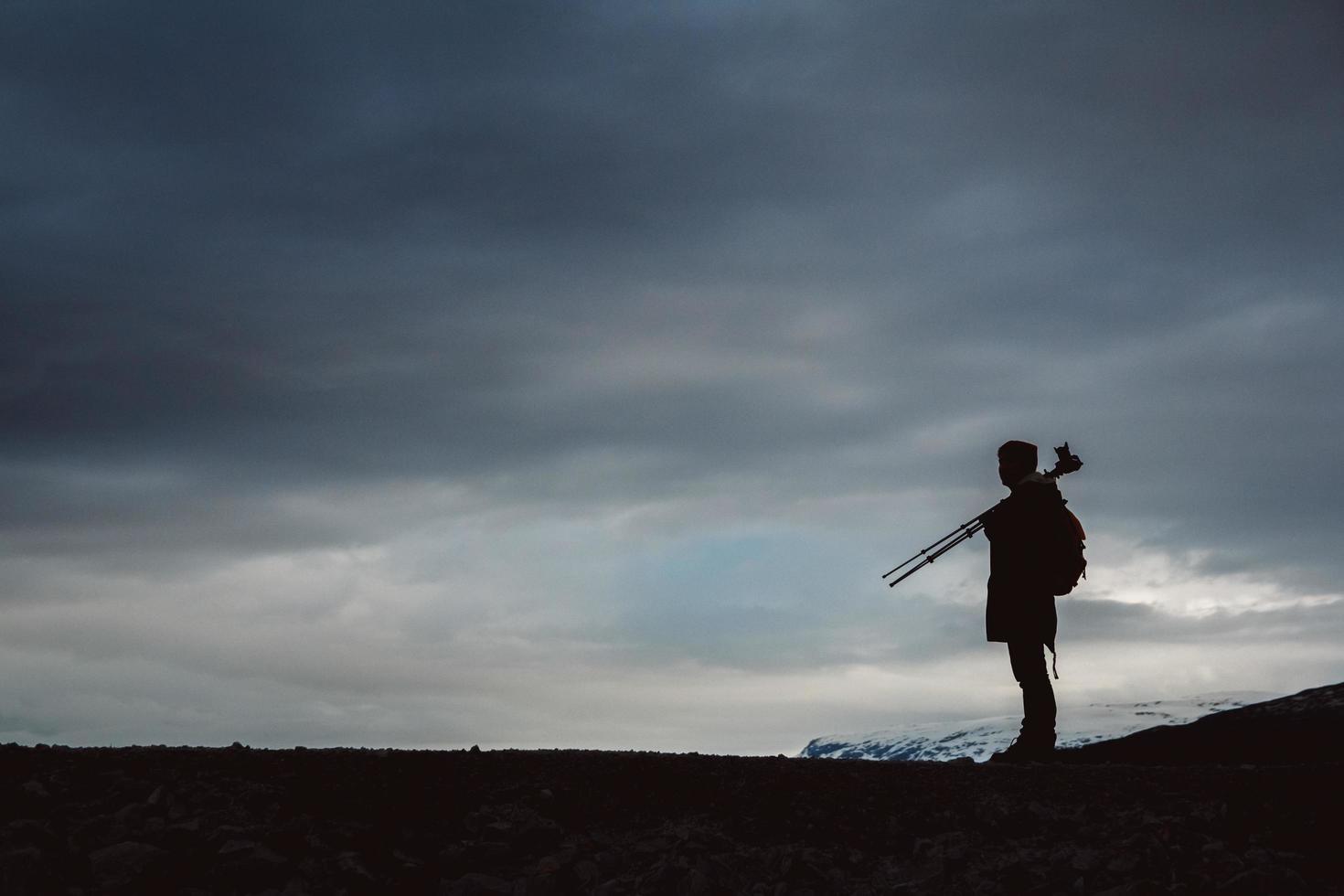 silhouette d'un photographe ou d'un voyageur avec trépied debout sur pierre photo