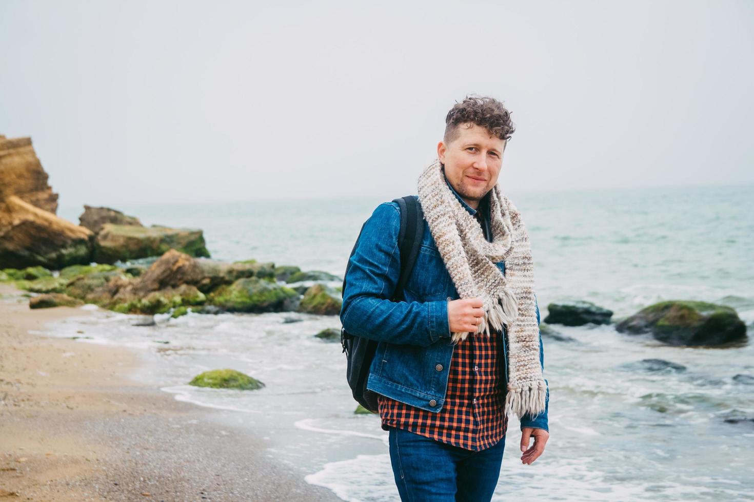 homme avec un sac à dos debout près d'un rocher contre une mer magnifique photo