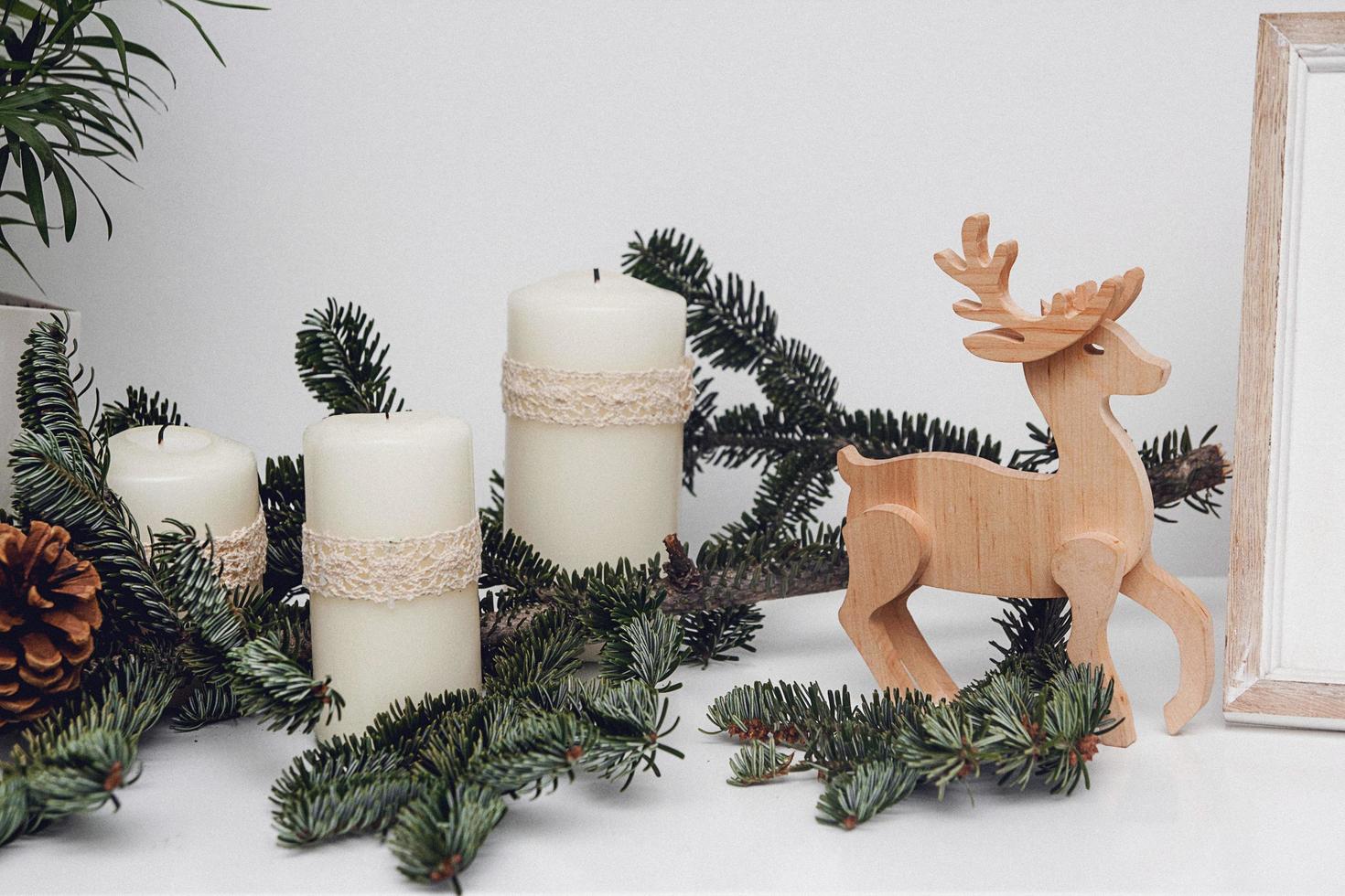 trois bougies de noël, boules, branche de pin et cerf en bois photo