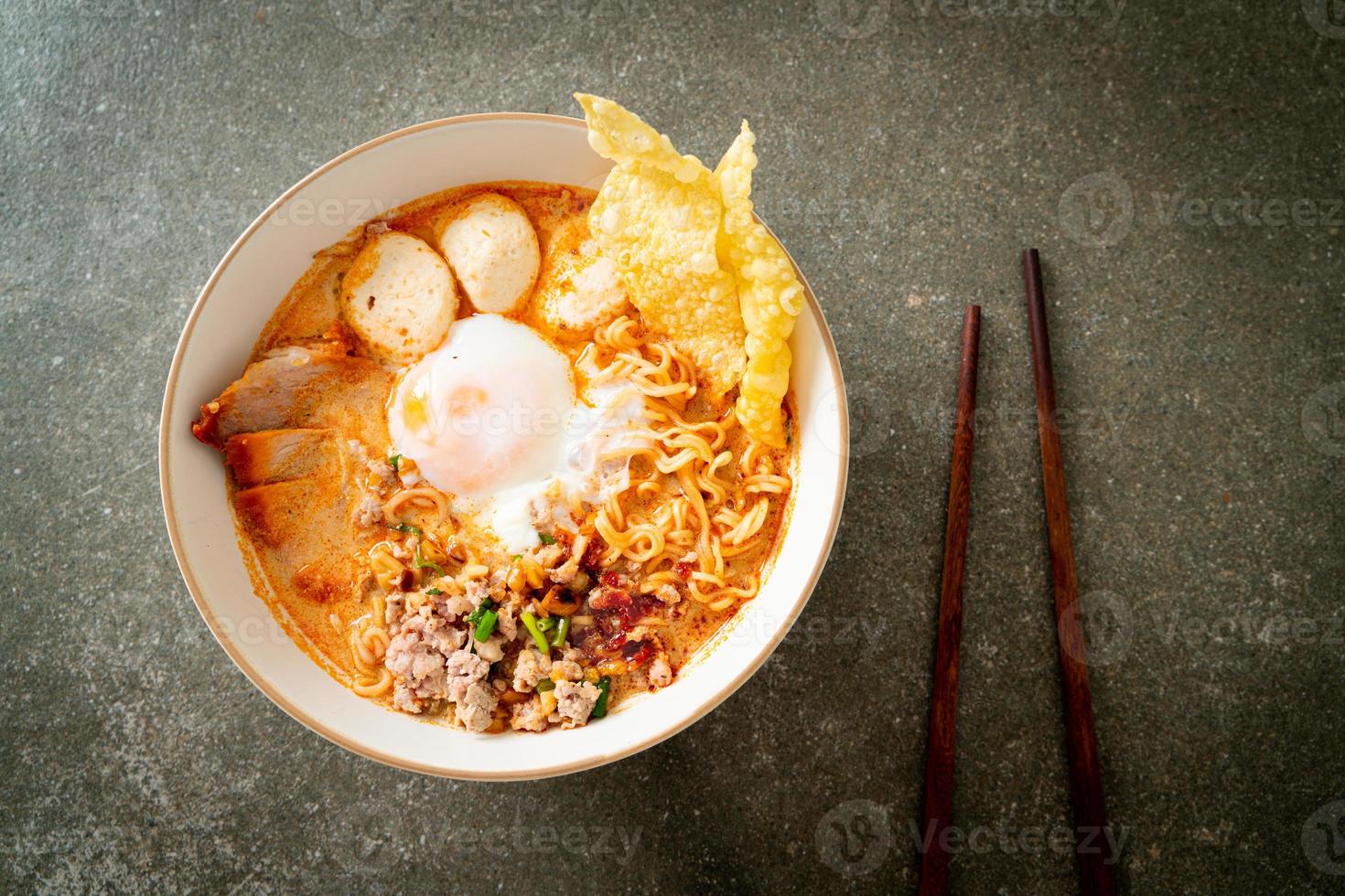 nouilles instantanées au porc et boulettes de viande dans une soupe épicée ou nouilles tom yum à l'asiatique photo