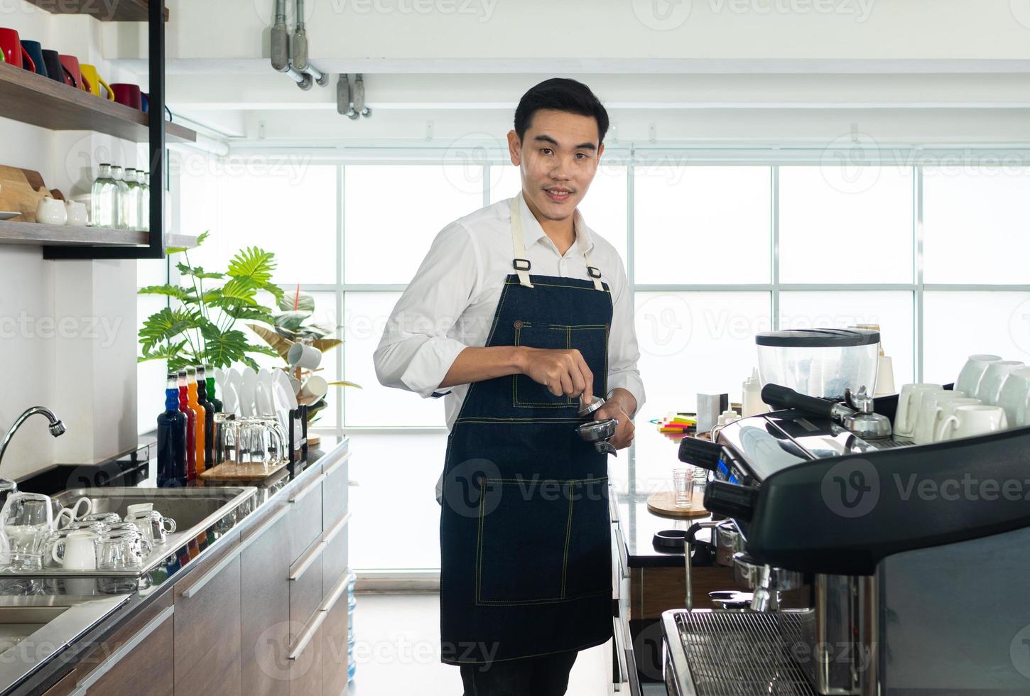 barista asiatique utilisant un moulin à café pour griller les grains de café photo