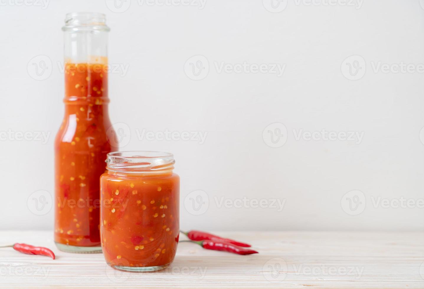 piment ou sauce chili en bouteille et pot sur fond de bois photo