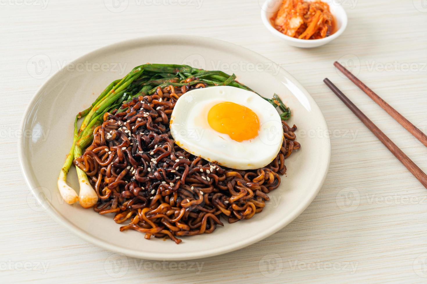 nouilles instantanées séchées faites maison à la sauce noire épicée coréenne avec œuf au plat et kimchi photo
