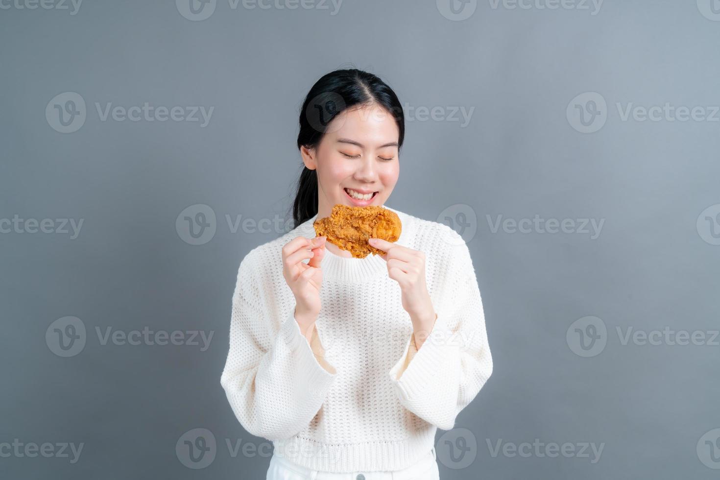 portrait d'une jeune fille asiatique heureuse montrant une carte de crédit en plastique tout en tenant un téléphone portable sur fond gris photo