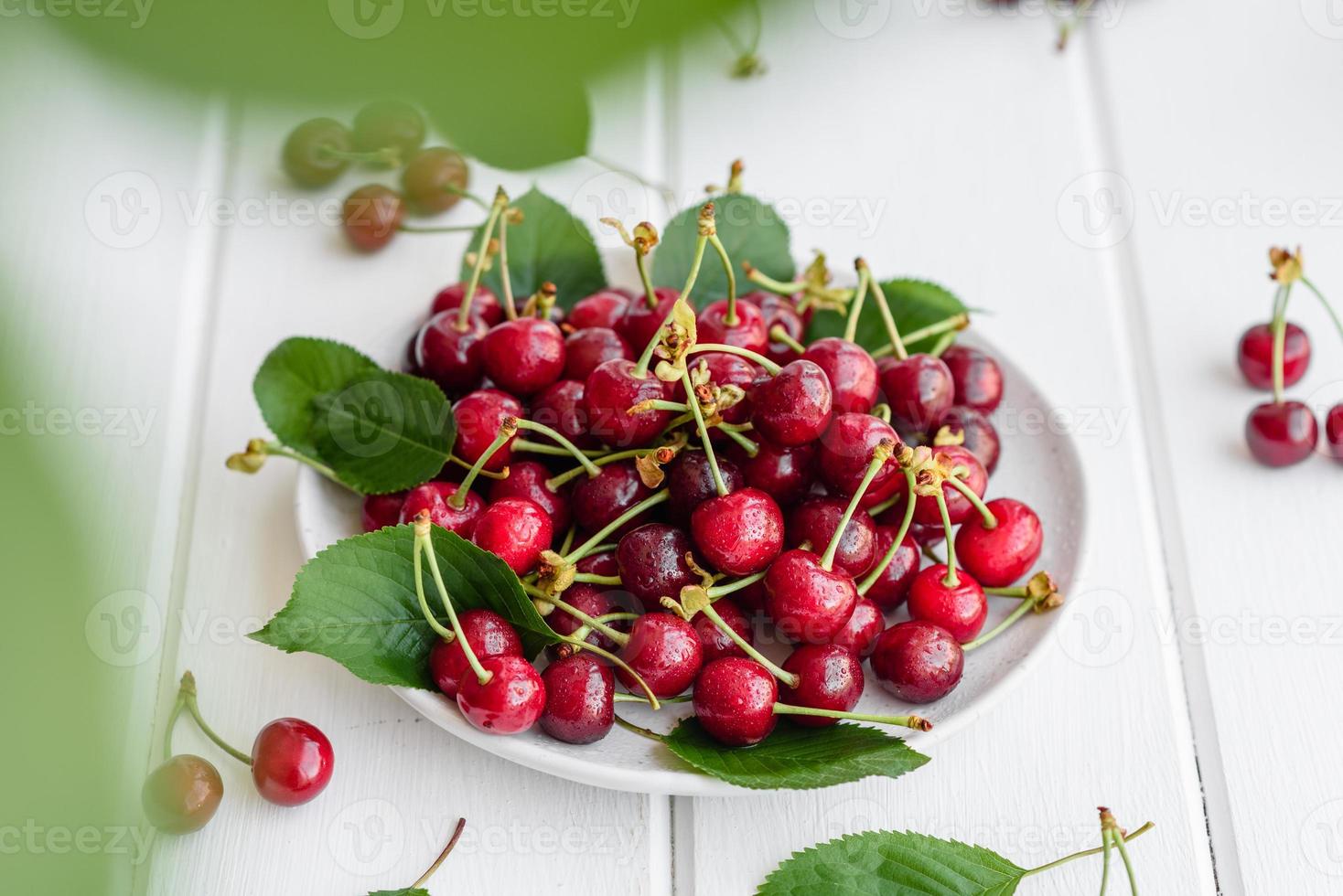 De délicieuses baies de cerises rouges lumineuses fraîches déchirées dans le jardin d'été photo