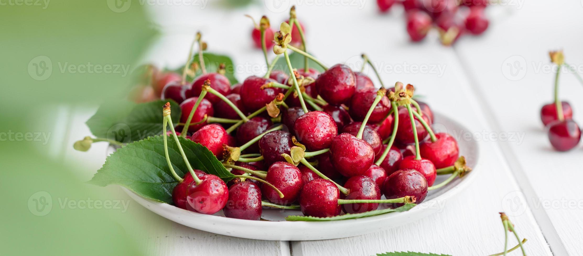 De délicieuses baies de cerises rouges lumineuses fraîches déchirées dans le jardin d'été photo