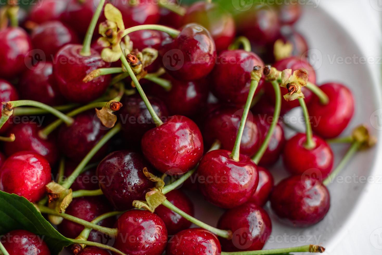 De délicieuses baies de cerises rouges lumineuses fraîches déchirées dans le jardin d'été photo