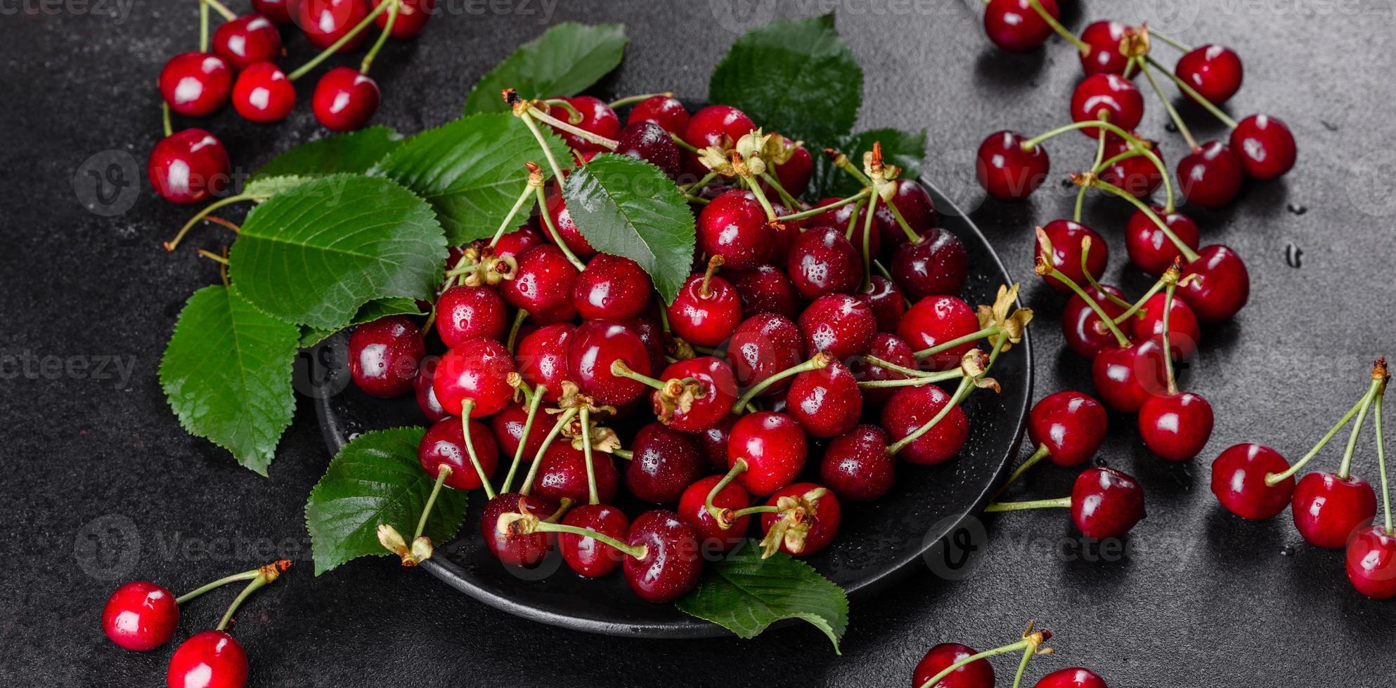 De délicieuses baies de cerises rouges lumineuses fraîches déchirées dans le jardin d'été photo