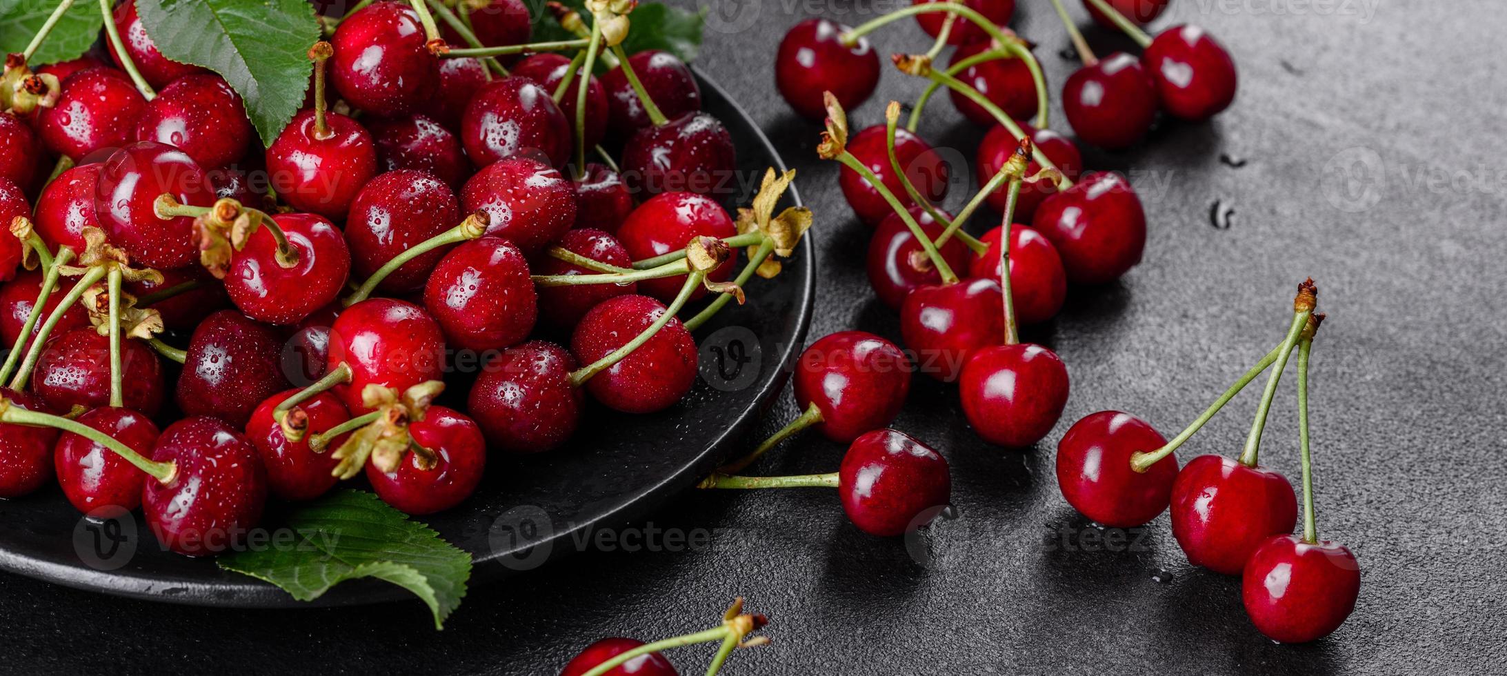 De délicieuses baies de cerises rouges lumineuses fraîches déchirées dans le jardin d'été photo