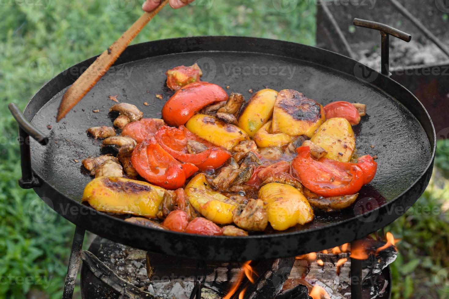 les légumes frais sont cuits dans une poêle à griller à feu ouvert photo