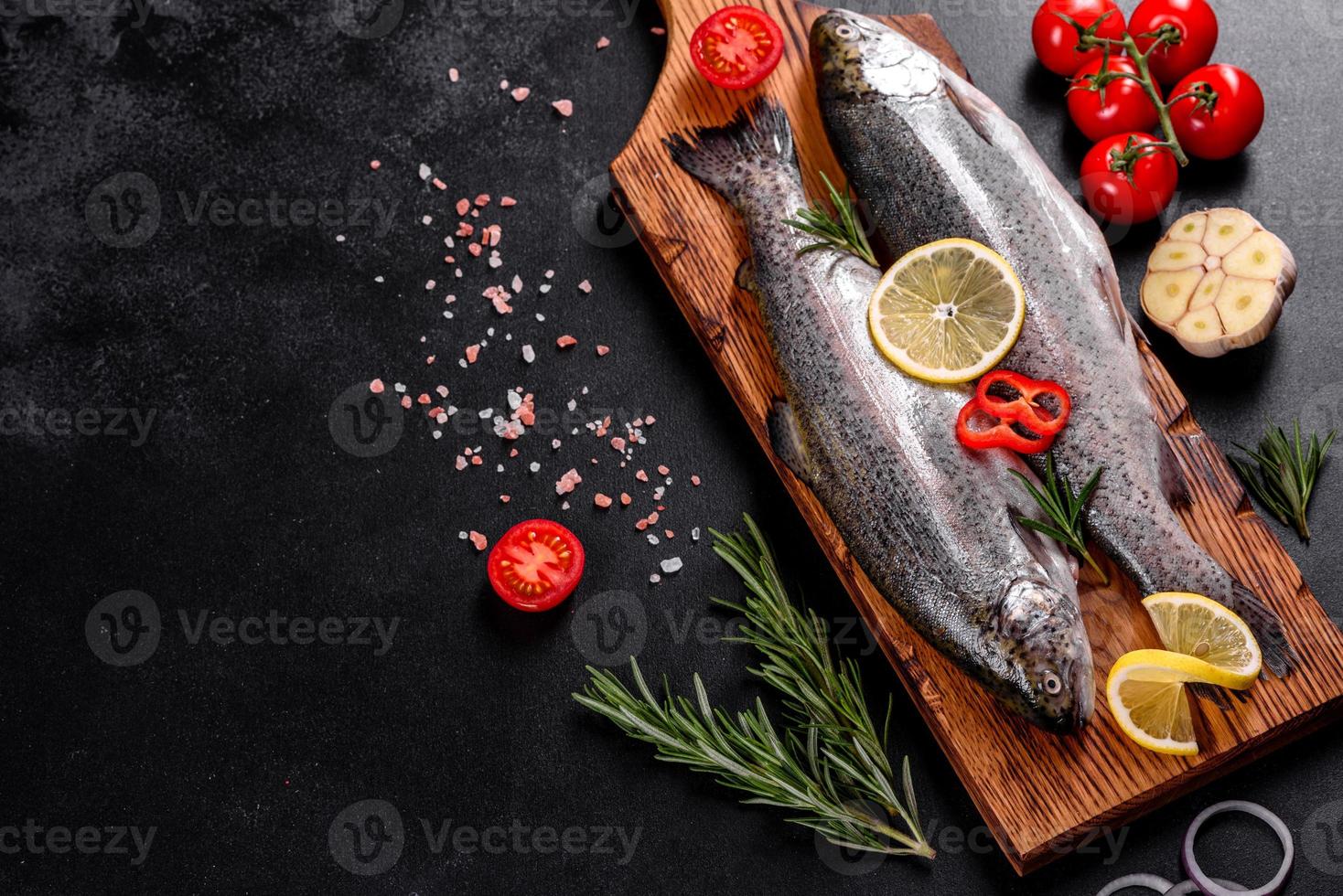 la truite crue se trouve sur une planche à découper en pierre noire sur une table en béton foncé photo