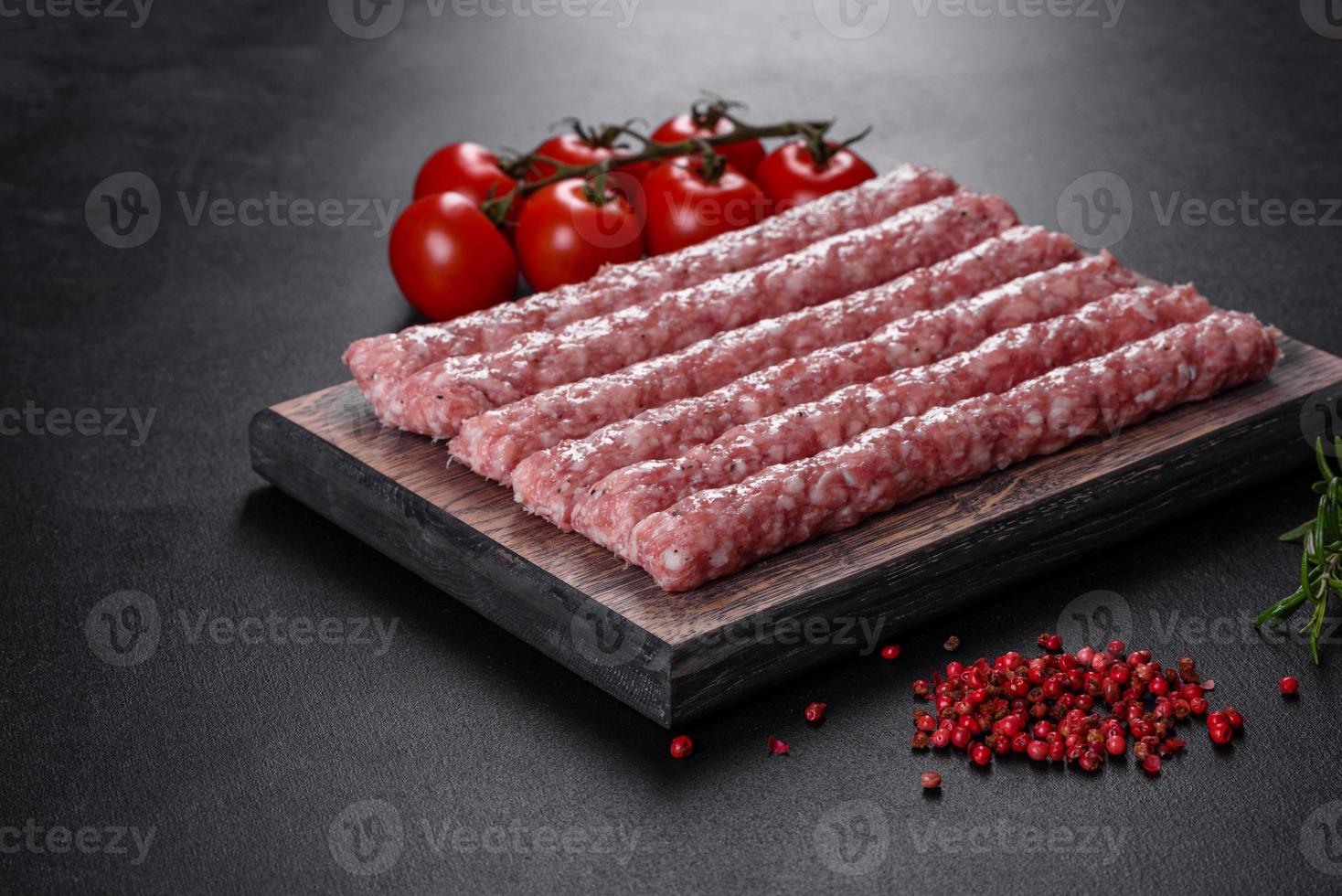 saucisses de porc crues fraîches aux épices sur une planche à découper en bois photo