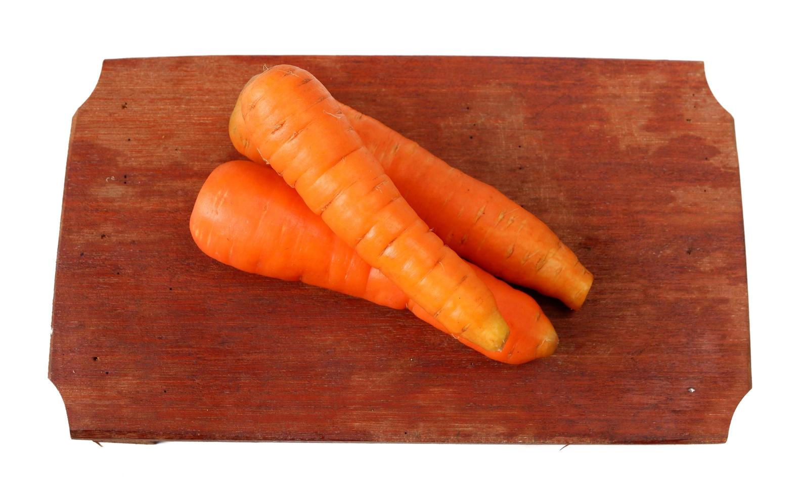 Carottes sur une planche à découper en bois isolé sur fond blanc photo