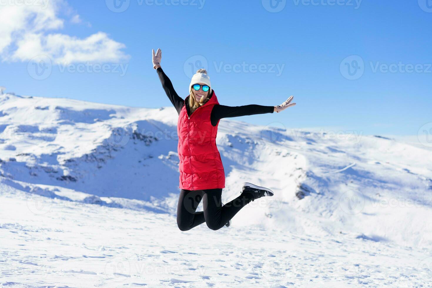 insouciant Jeune femme sauter avec élevé bras sur neige terrain photo