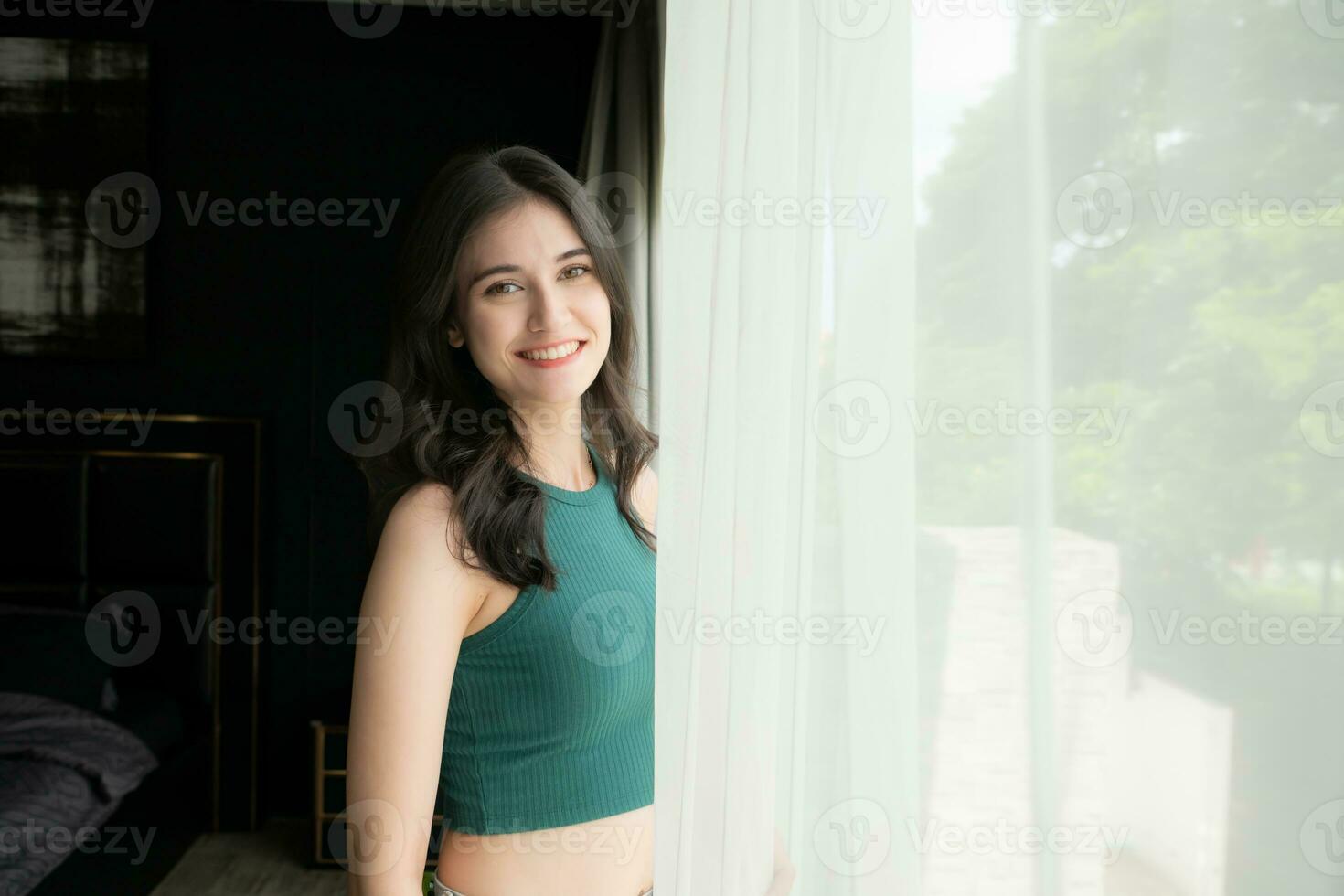 portrait de une magnifique asiatique femme dans vert chemise permanent près le fenêtre photo