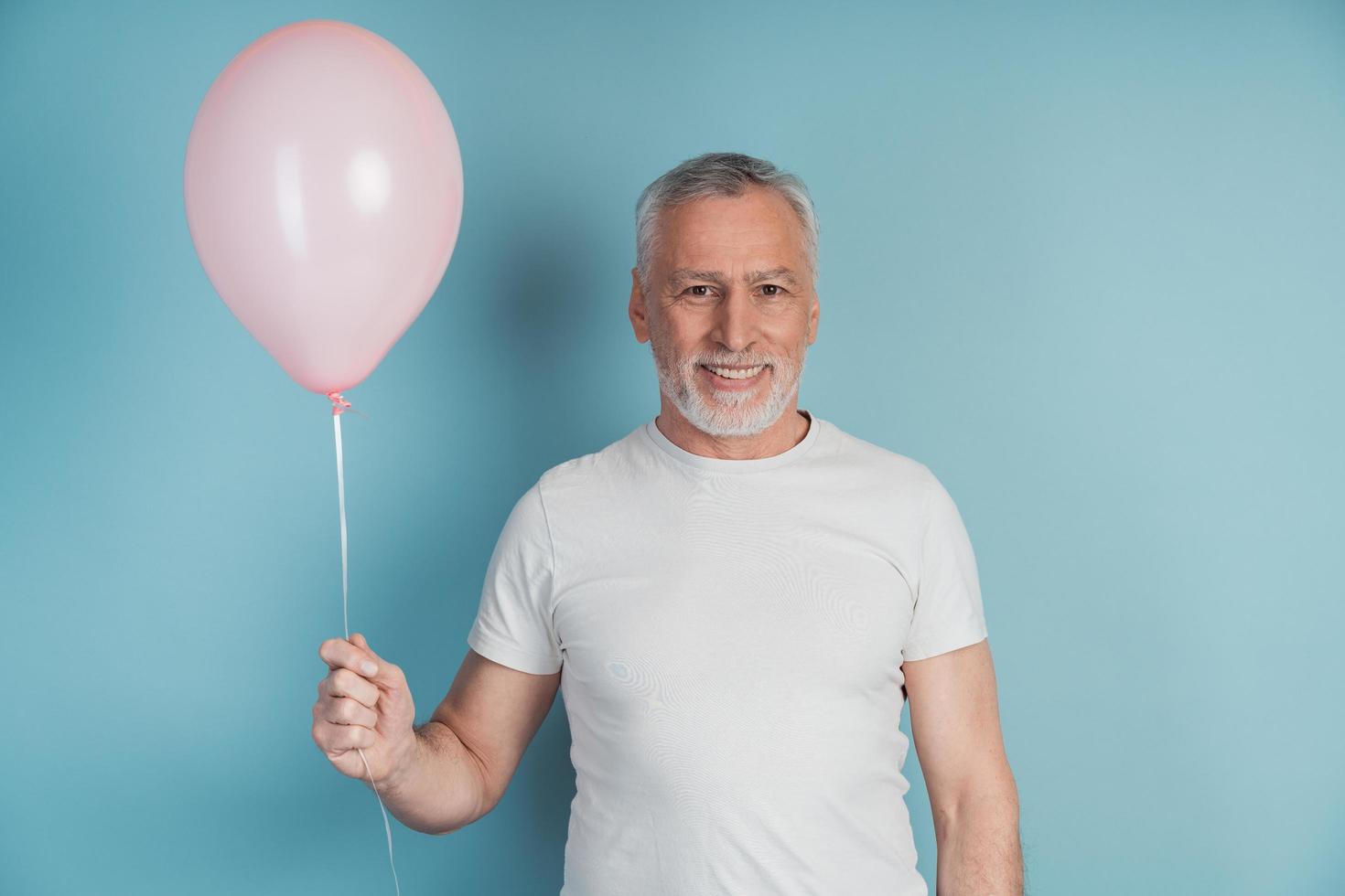 heureux retraité en t-shirt blanc tenant un ballon rose photo
