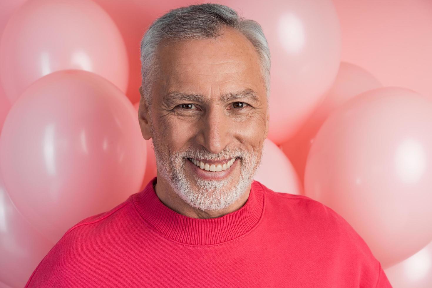 homme sincère et séduisant souriant sur fond de ballons roses photo