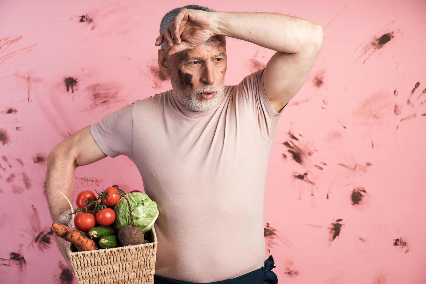 homme âgé fatigué tenant un panier avec des légumes photo