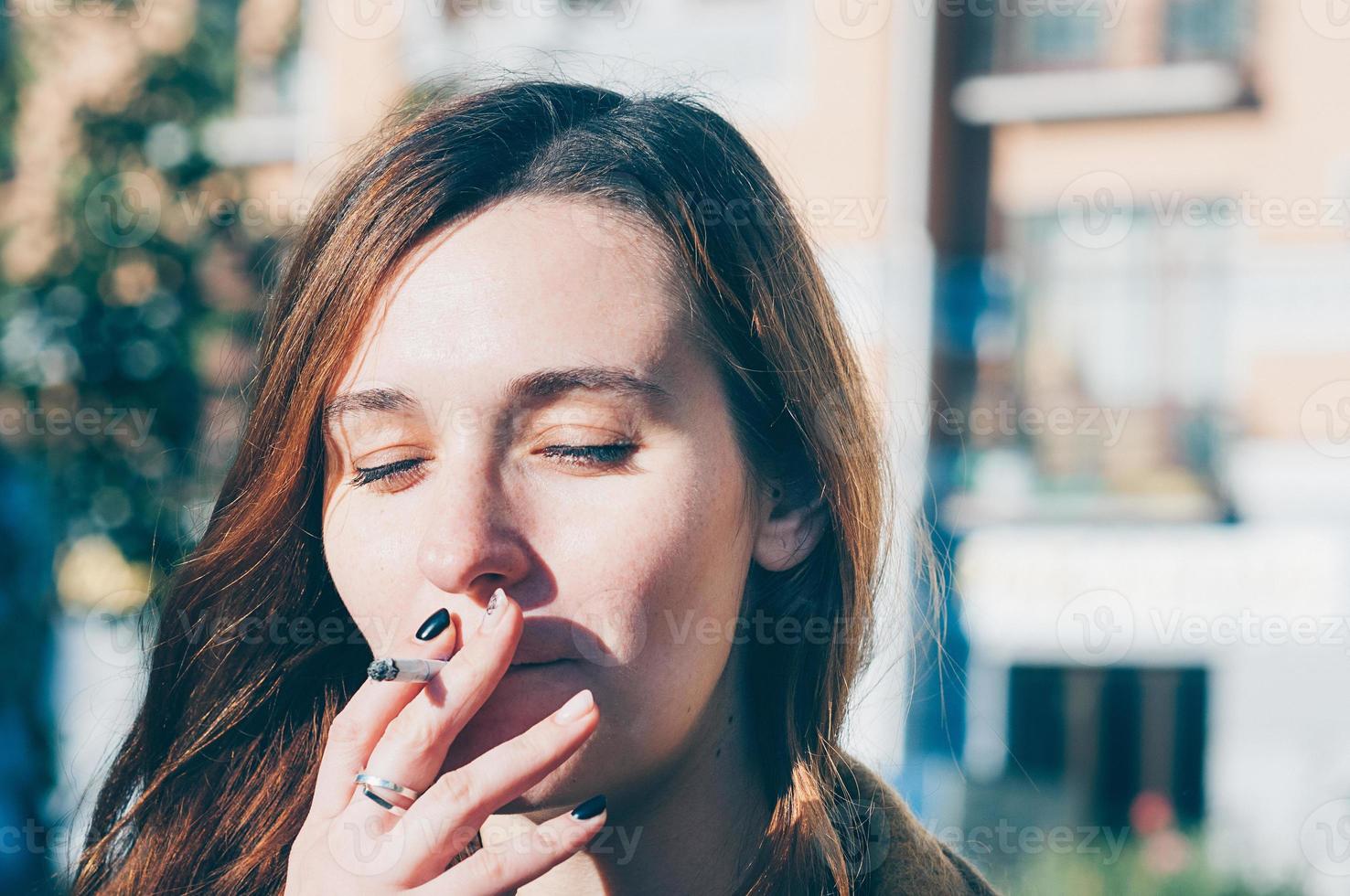 jolie fille fume une cigarette à l'extérieur photo