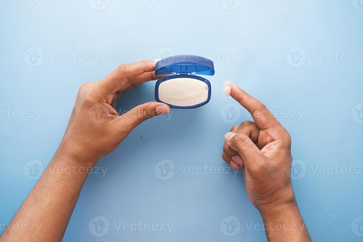 vue de dessus de la main de l'homme à l'aide de vaseline sur fond bleu photo