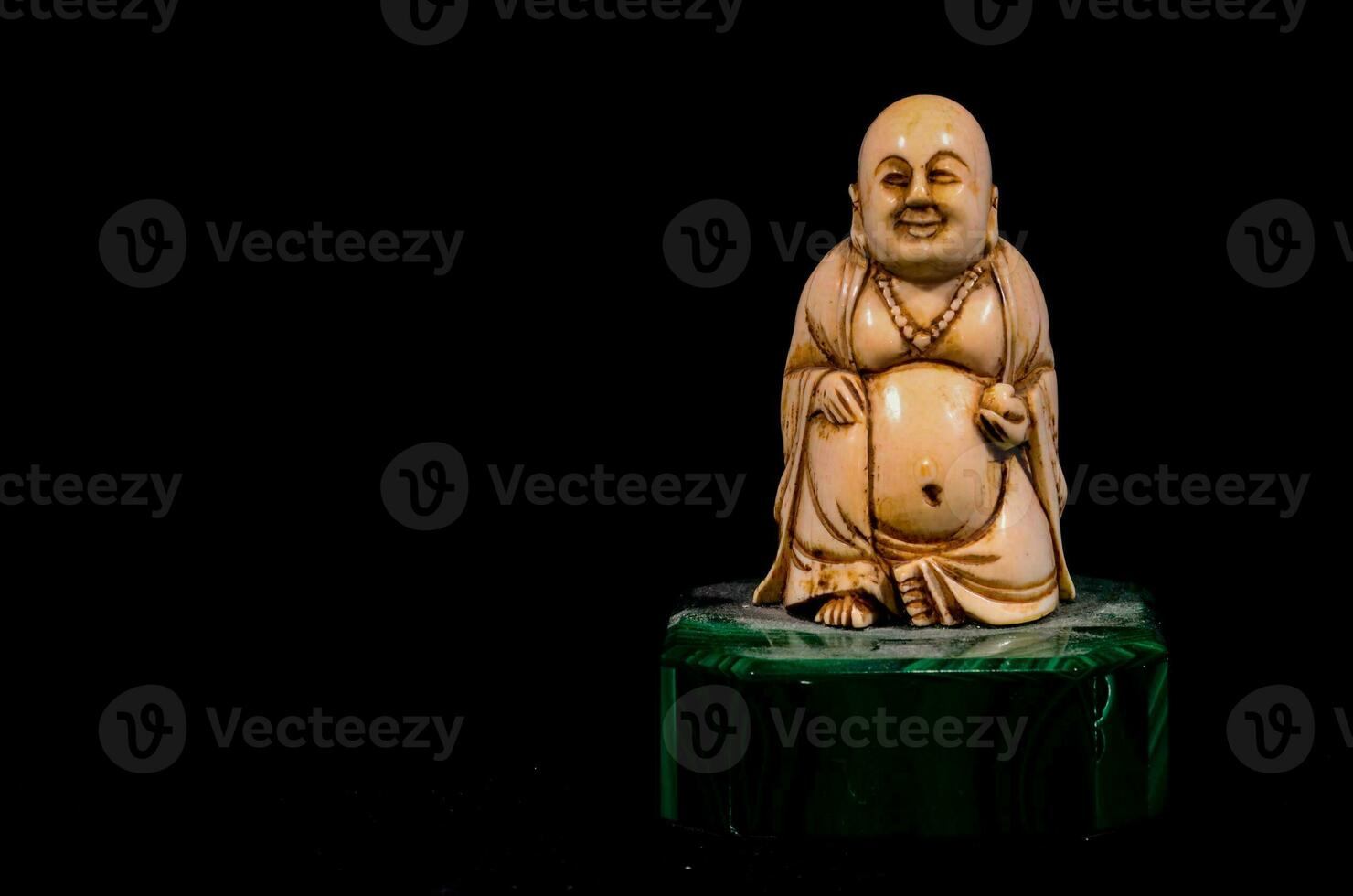 une petit statue de une Bouddha séance sur une vert marbre base photo