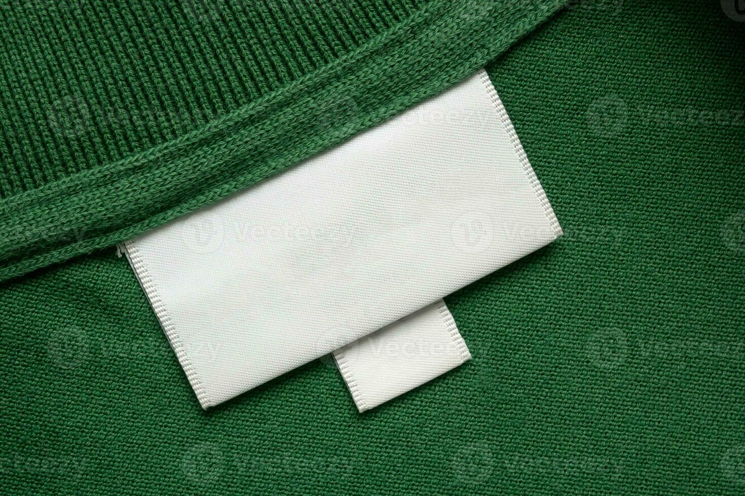 Vide blanc blanchisserie se soucier vêtements étiquette sur vert chemise en tissu texture Contexte photo