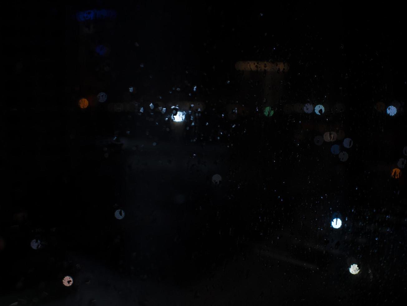 gouttes de pluie sur la fenêtre avec des lumières de bokeh de rue photo