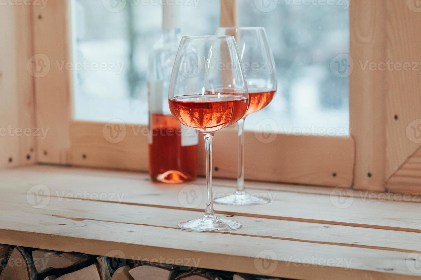 une bouteille de vin rosé et deux verres remplis sur un rebord de fenêtre photo