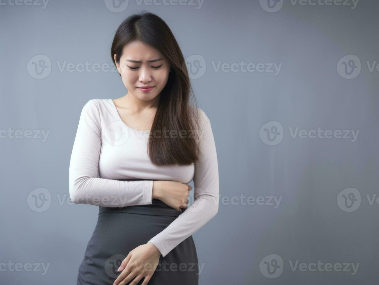 asiatique femme apparaît à être dans douleur sur gris Contexte ai génératif photo