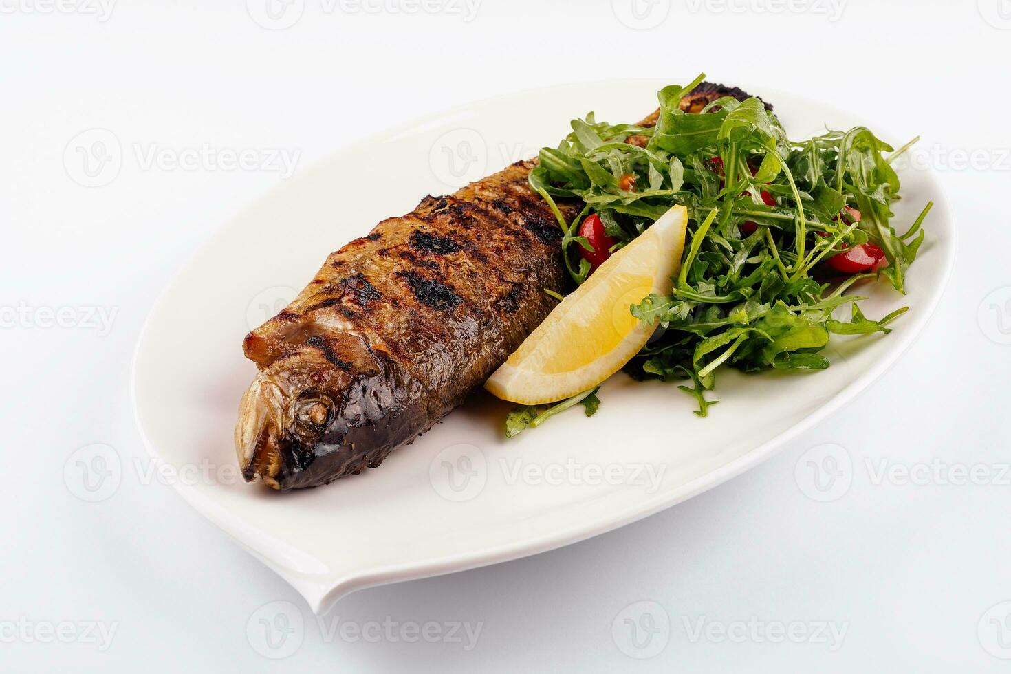 Poisson daurade grillé, citron, roquette sur plaque blanche photo