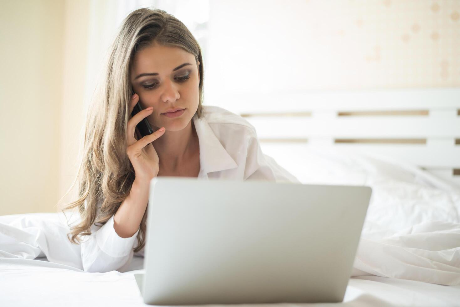 heureuse belle femme travaillant sur un ordinateur portable sur le lit dans la maison photo