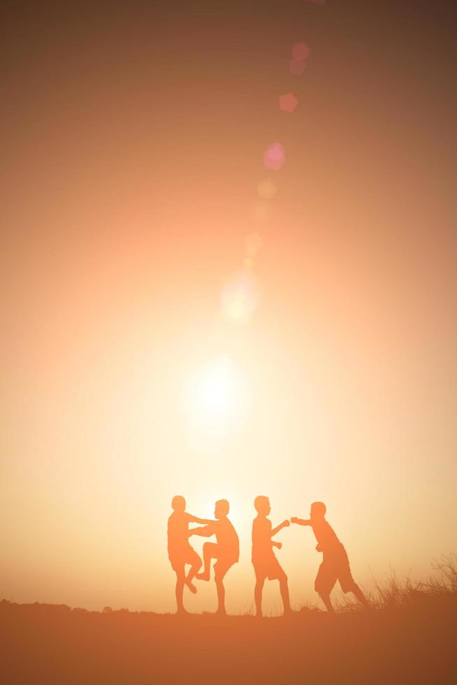 enfants jouant sur le temps heureux du coucher du soleil d'été photo