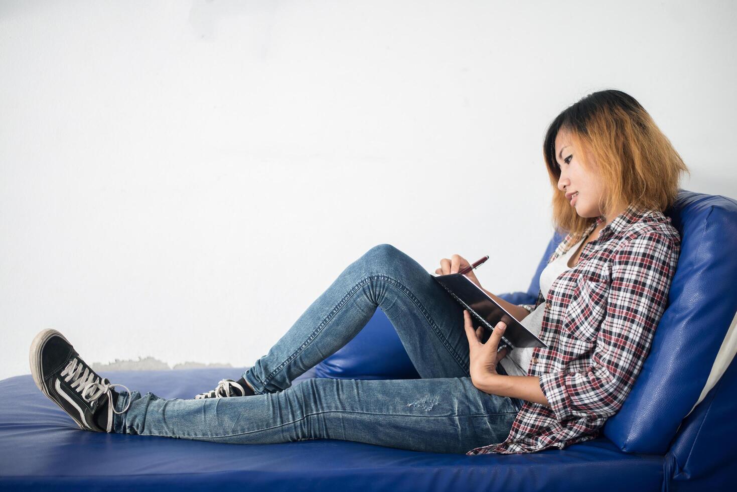 jeune femme hipster écrit sur le bloc-notes allongé à la maison. photo