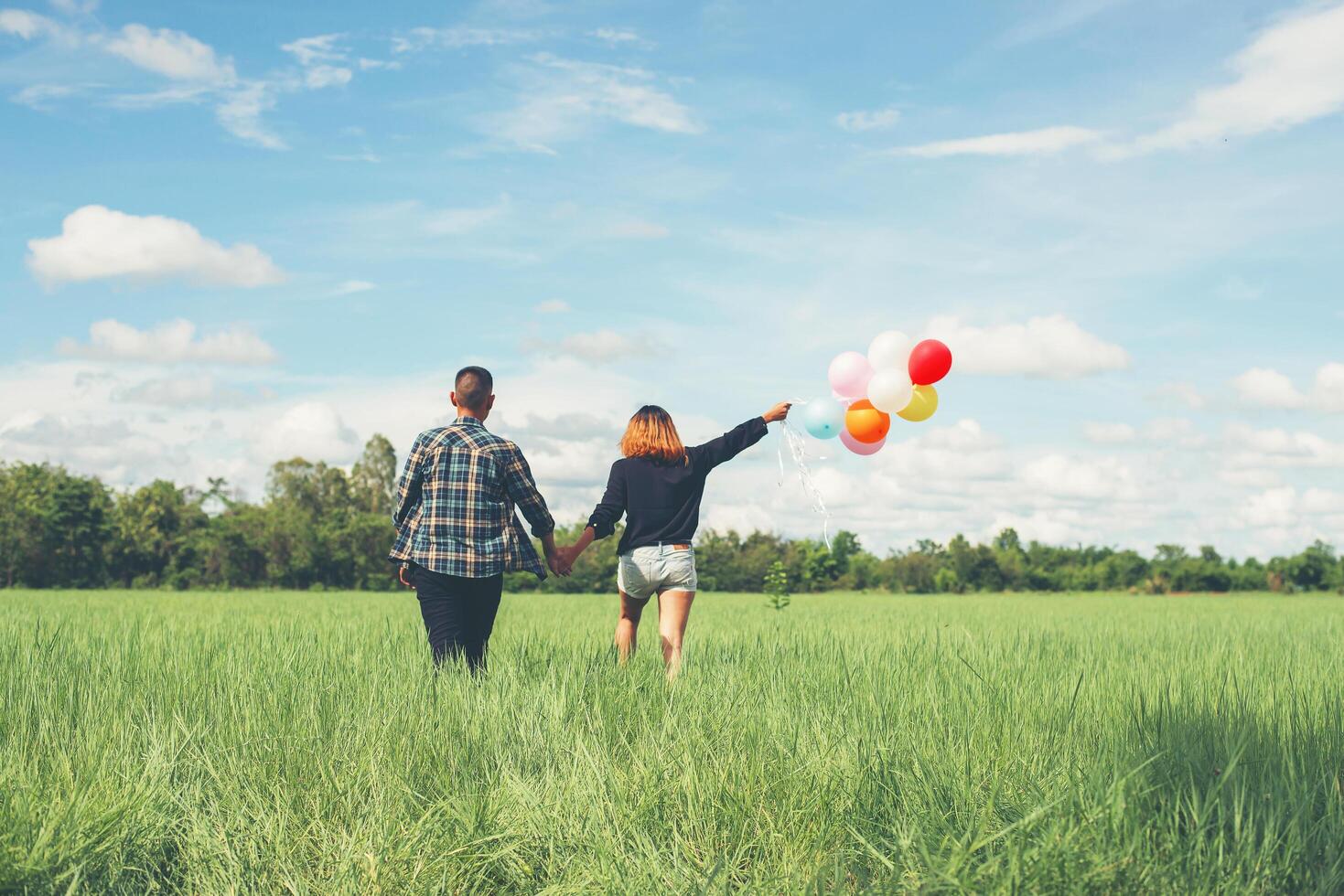 dos d'un jeune couple asiatique heureux tenant un ballon et marchant ensemble. photo