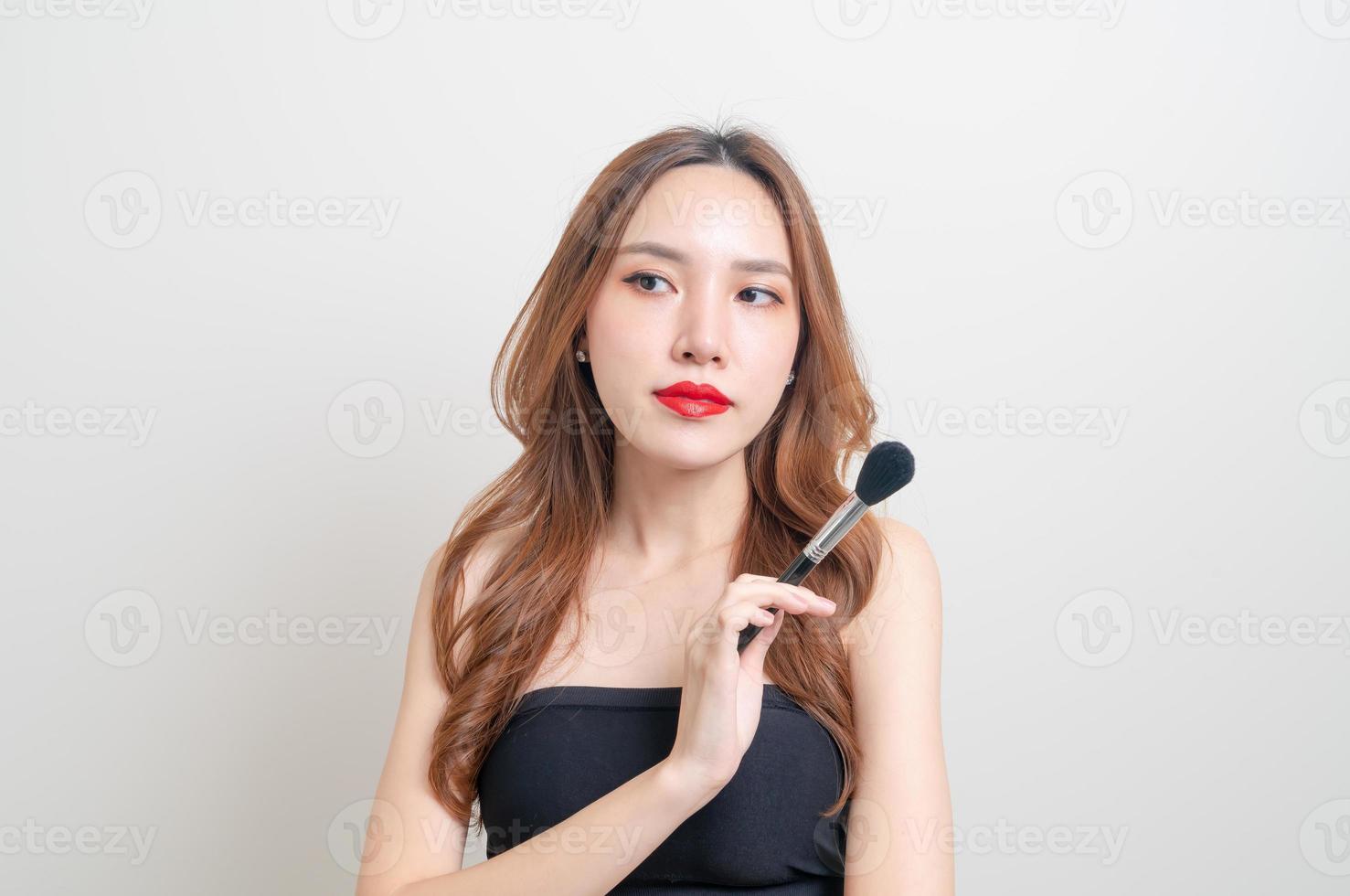 Portrait belle femme asiatique avec pinceau de maquillage sur fond blanc photo