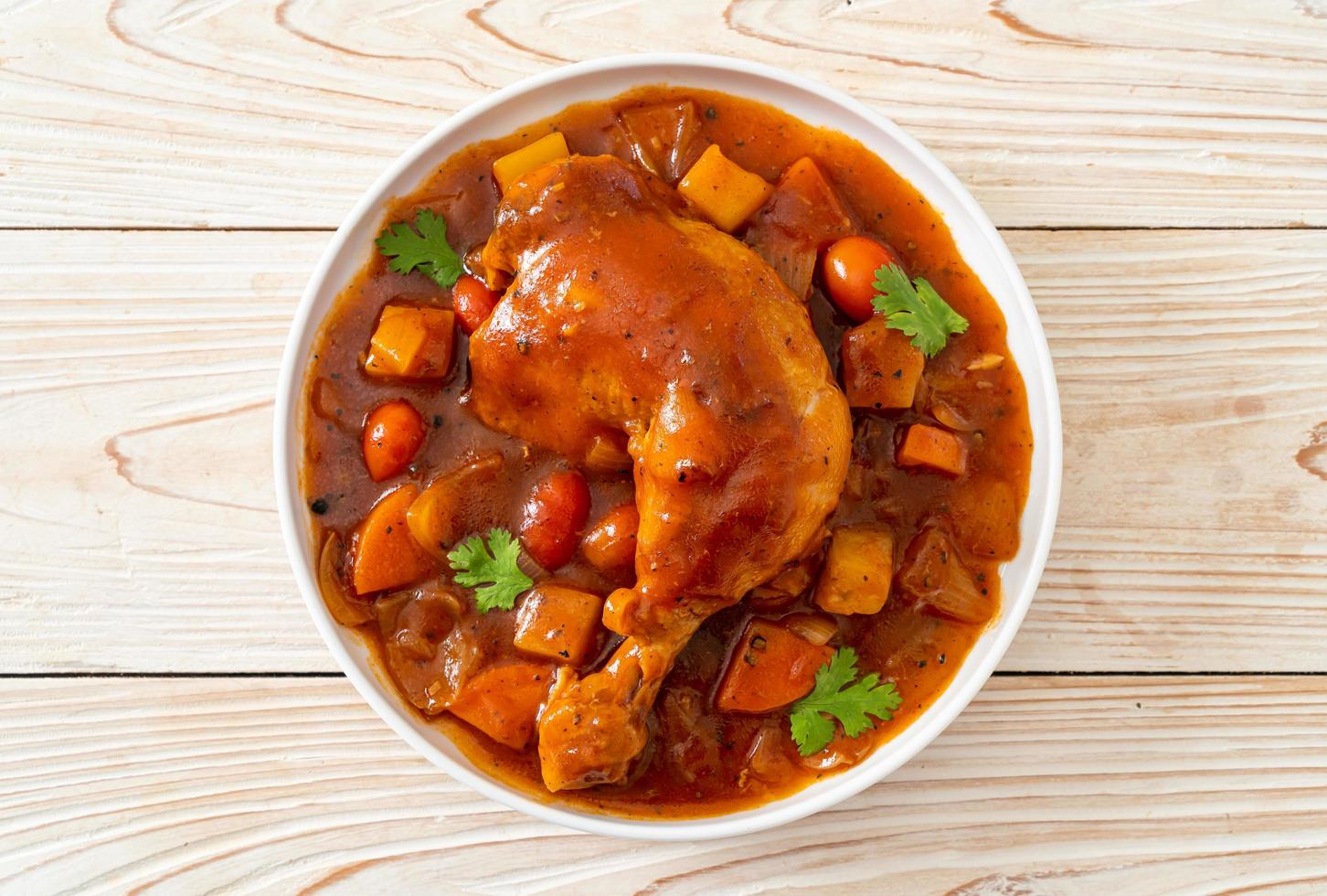 ragoût de poulet maison avec tomates, oignons, carottes et pommes de terre sur assiette photo