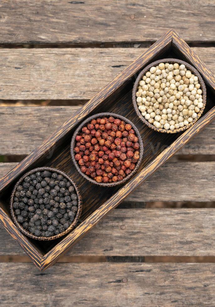 grains de poivre blanc rouge et noir biologique dans un présentoir en bois photo