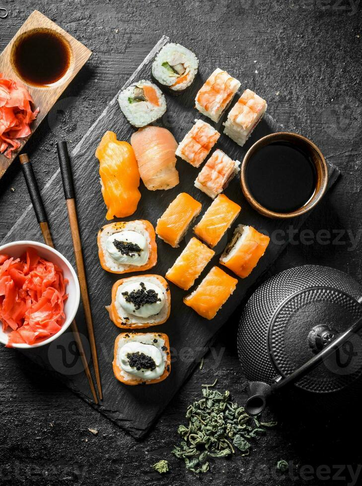 Japonais Sushi et Rouleaux avec soja sauce, gingembre et vert thé dans une théière. photo