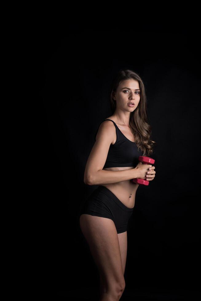 belle jeune femme faisant des exercices physiques avec des haltères. photo