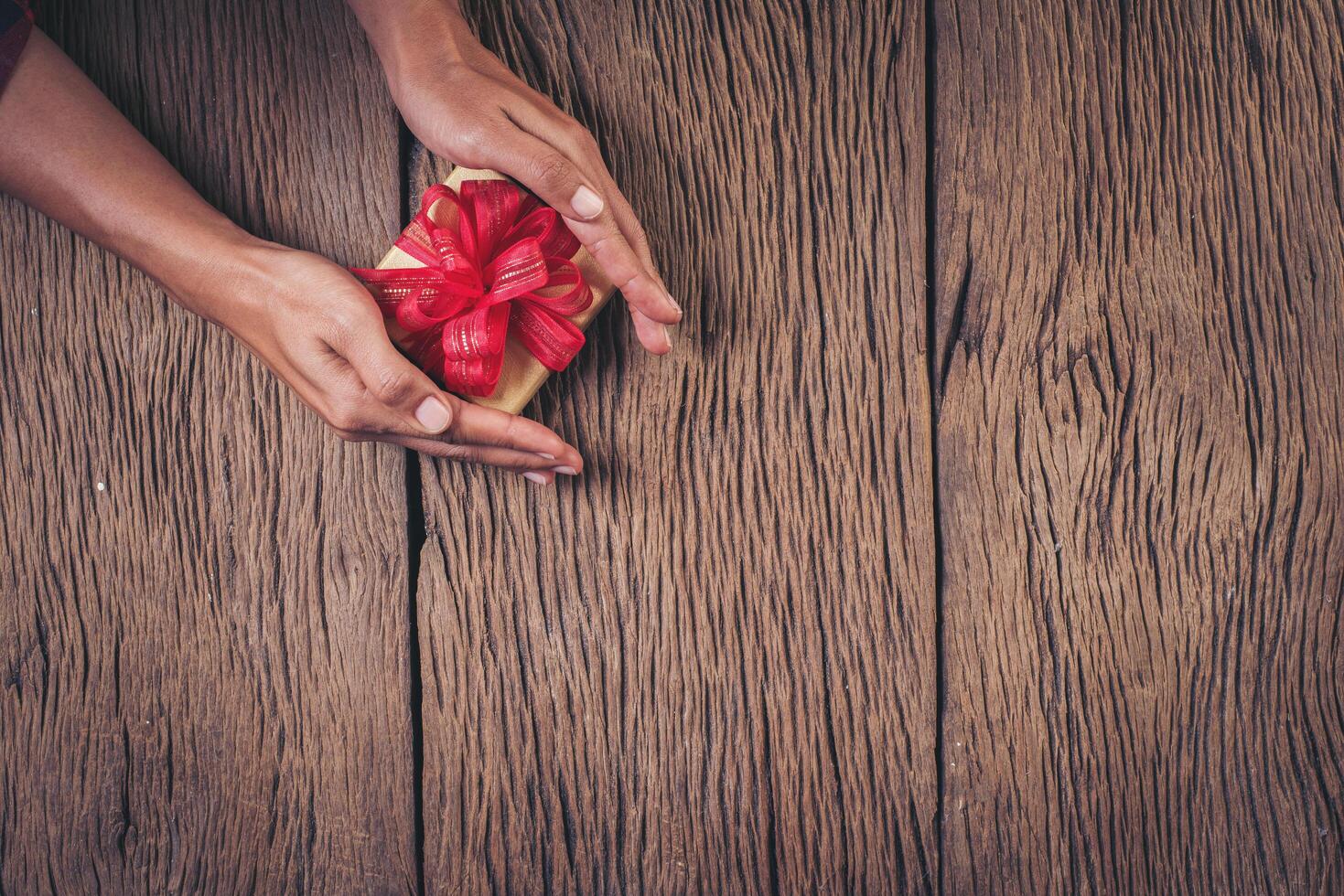 vue de dessus main tenant une boîte-cadeau sur fond de bois. photo