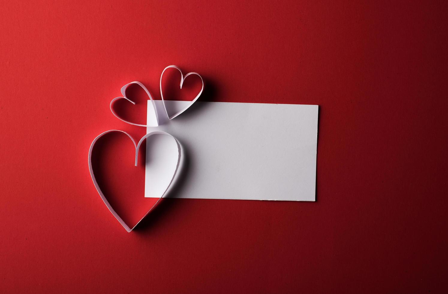 papier coeur rouge et blanc avec carte de note sur fond rouge. photo