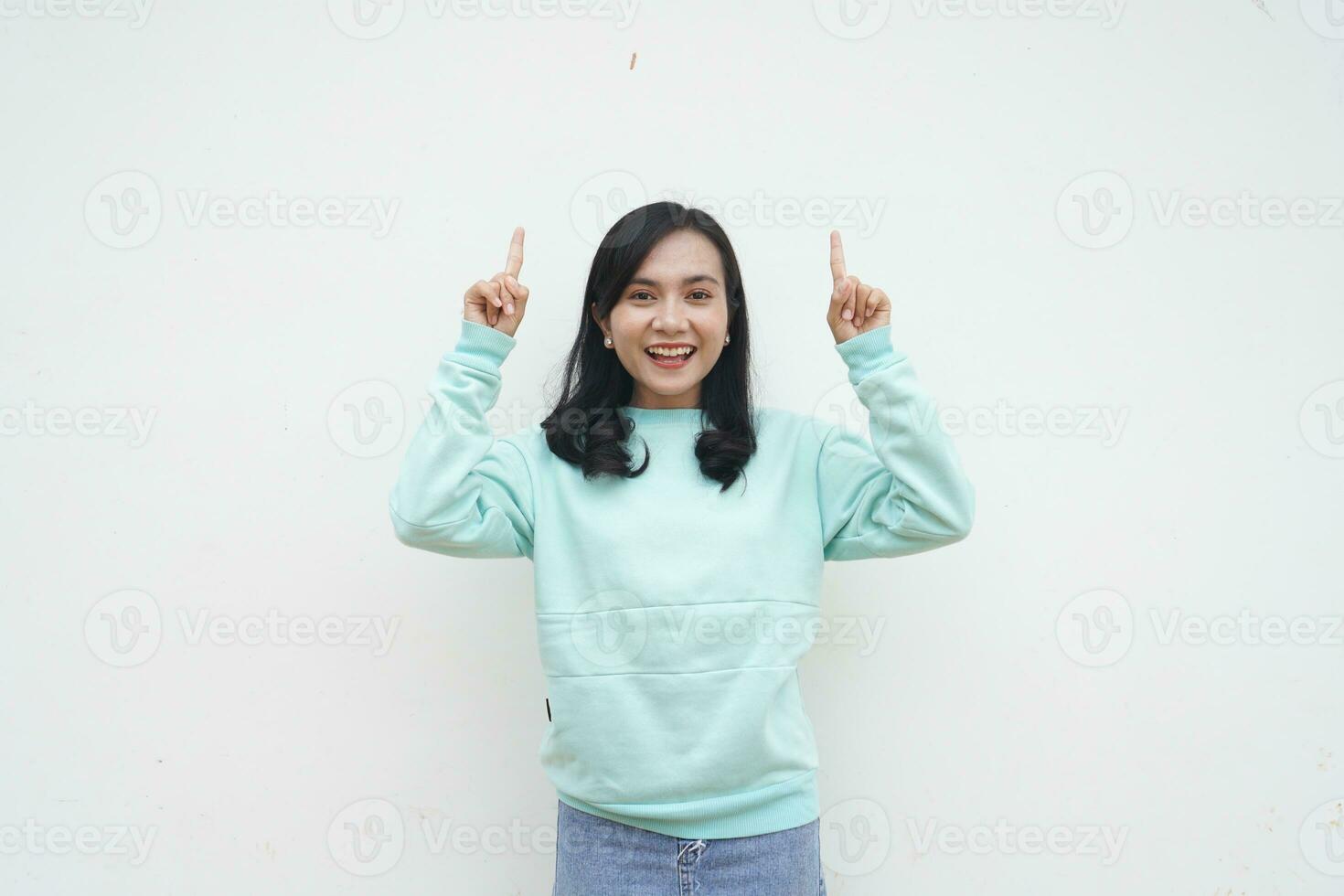 portrait indonésien magnifique femme portant lumière bleu chandail sourire dan content geste doigt montrer du doigt à blanc Contexte photo
