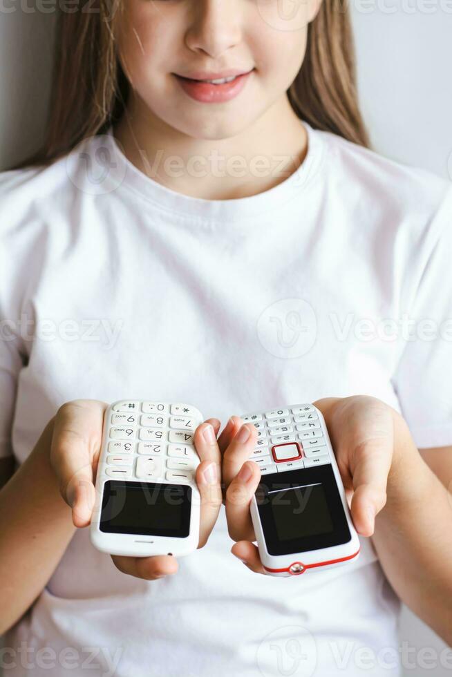 deux blanc démodé bouton téléphones dans le mains de une fille verticale vue photo